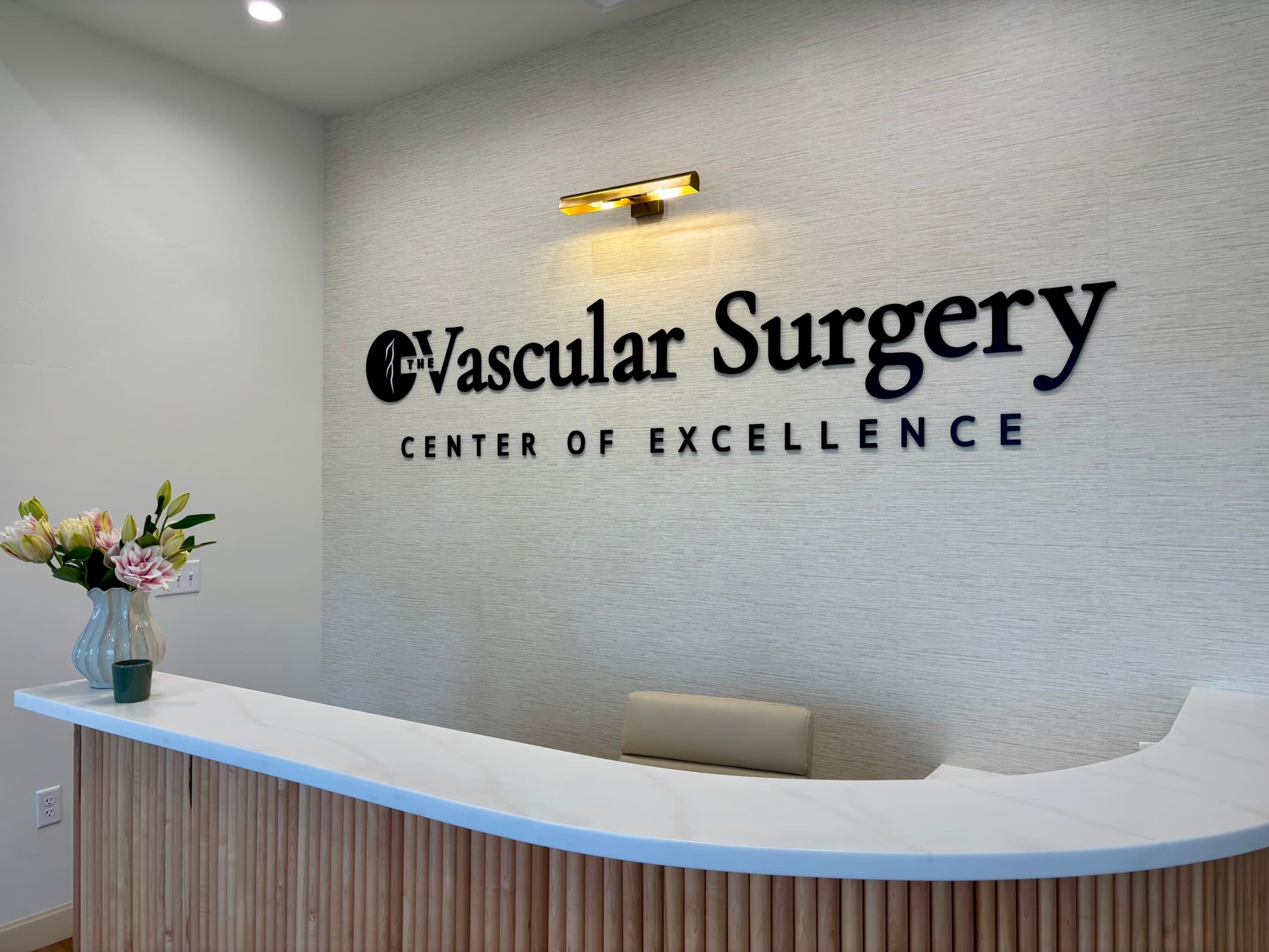 The reception desk and wall sign inside The Vascular Surgery Center of Excellence